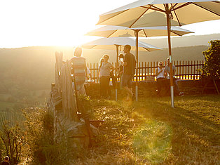 Personen genießen draußen den Sonnenuntergang